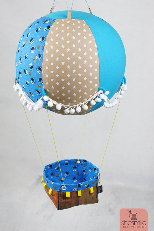 Ein Adventskalender Adventsballon mit Krümelmonster in blau-gelb für mein Patenkind. Nähanleitung und Schnittmuster gestaltet als PDF-E-Book von shesmile für einen Adventskalender und Kinderzimmerdeko Adventsballon in Form eines Heißluftballons. 24 kleine Geschenke oder ein Musikwürfel finden ihren Platz an den Halteschlaufen am oder im Körbchen.