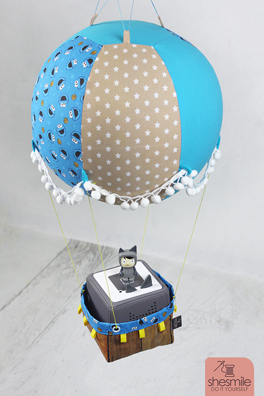 Nähanleitung und Schnittmuster gestaltet als PDF-E-Book von shesmile für einen Adventskalender und Kinderzimmerdeko Adventsballon in Form eines Heißluftballons. 24 kleine Geschenke oder ein Musikwürfel finden ihren Platz an den Halteschlaufen am oder im Körbchen. Krümelmonster und Toniebox.
