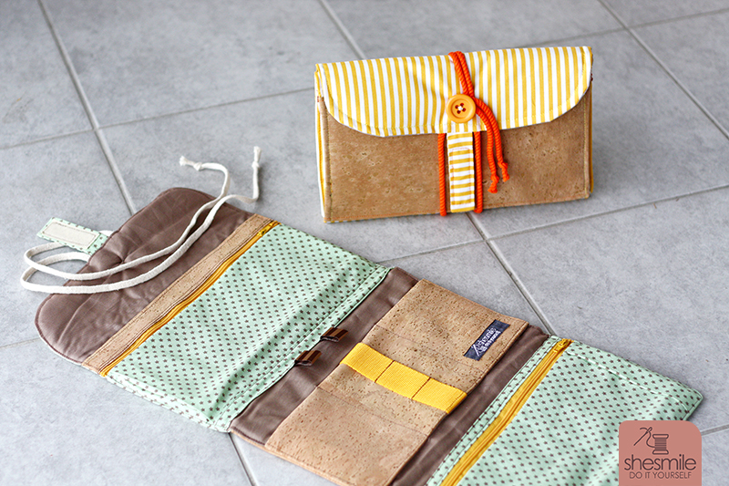 Eine Kulturtasche "Hanging3" in gelb-orange mit Designelementen aus Kork. Augeklappt und zusammengerollt.