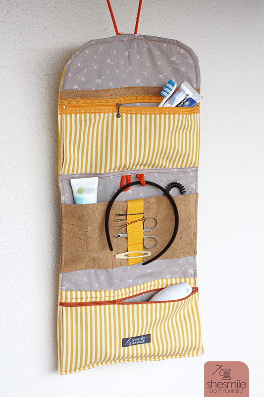Eine Kulturtasche "Hanging3" in gelb-orange mit Designelementen aus Kork. Um den Platz am Waschbecken-Rand können sich andere streiten.