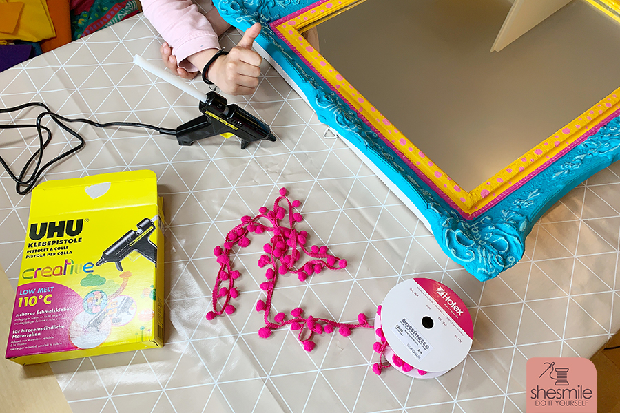 Ein Spiegel nach Maß mit Bommelborte. Ein alter Bilderrahmen wird zum Spiegel für das Kinderzimmer. Ein Upcycling Bastelprojekt von shesmile DIY.