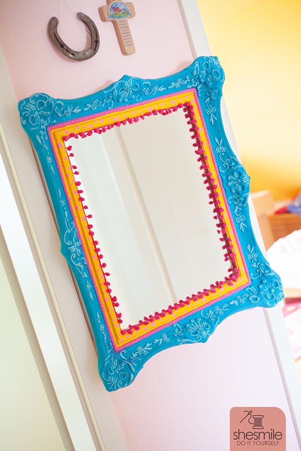 Ein Spiegel nach Maß mit Bommelborte. Ein alter Bilderrahmen wird zum Spiegel für das Kinderzimmer. Ein Upcycling Bastelprojekt von shesmile DIY.