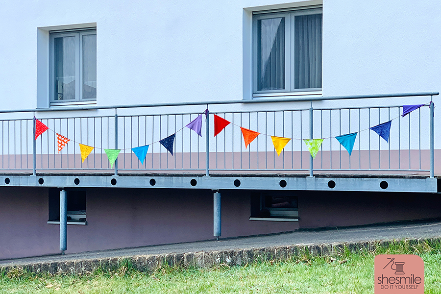 Nähanleitung und Schnittmuster gestaltet als PDF-E-Book von shesmile für eine Wimpelkette in Regenbogenfarben. Zum Aufhängen am Balkon, Treppengeländer, Zaun oder als Kinderzimmer- und Geburtstags-Deko.