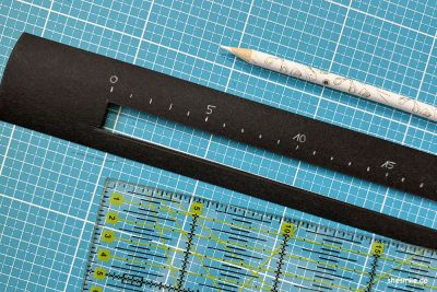 Einen Streifen SnapPap in 5 x 50 cm zuschneiden. Einen Schlitz von 1,5 x 40 cm aus dem Streifen schneiden. Der Schlitz liegt mittig ausgerichtet, 1 cm vom unteren Rand.
