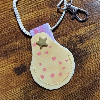 Ich habe SnapPap genommen, gelb und lila mit Stempelfarbe eingefärbt und gestempelt mit Herzchen und dem Text "for you". Das Bändchen ist gold/weiss, Karabiner und Sternchen Druckknopf runden das Ganze ab.