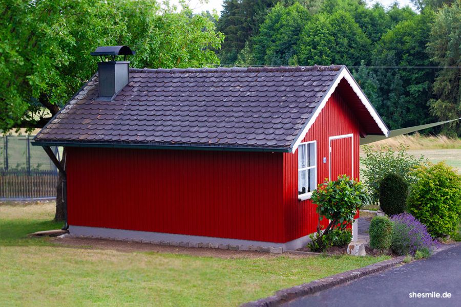Materialliste mit Ideensammlung für Hobby-Handwerkerinnen. Ein rotes Norweger Häuschen im bayerischen Garten. DIY renovieren und streichen des Gartenhäuschens.