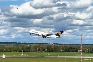 Vorfreude-Ausblick vom Besucherhügel auf den Flug LH452 von München (MUC) nach Los Angeles (LAX). Lufthansa Airbus A380 beim Starten beobachten mit shesmile.