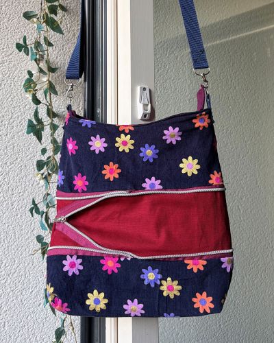 Für meine Schwägerin habe ich die Handtasche Zipkram von shesmile als Geburtstagsgeschenk genäht. Die Idee mit der expandierenden Handtasche fand ich klasse, und da ich durch mein voriges Projekt (Kulturbeutel Valta von Hansedelli) gerade entdeckt habe, dass Endlosreißverschlüsse gar nicht so schwer zu verarbeiten sind, habe ich mich gleich nochmal an welche gewagt! Als Material habe ich einen Rest Cordstoff vom letzten Hosenprojekt verwendet,  für den klappbaren Mittelteil beschichtete Baumwolle (Rest vom Kulturbeutel) und für das Innenfutter einen robusten Jerseystoff (auch Rest eines anderen Kleidungs-Nähprojekts). So ist in kurzer Zeit aus Materialien, die ich da hatte, eine tolle, farbenfrohe Tasche entstanden. Ich finde, sie macht direkt gute Laune beim Anschauen, ich hoffe, der Beschenkten gefällt sie auch!