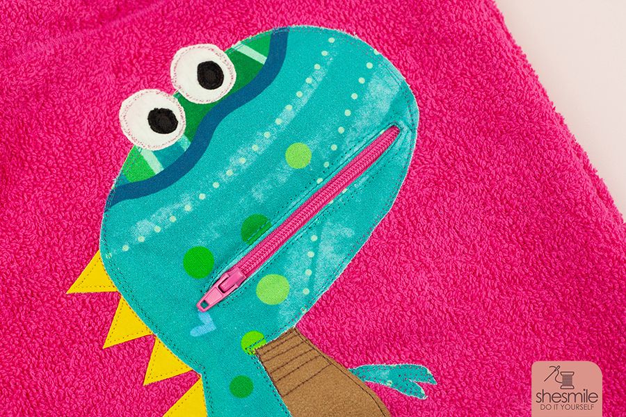 Ein Taschentier Dino mit Reißverschluss-Mund von Kleiner Polli-Klecks auf einem Frotteelo-Kulturbeutel aus Frottee von shesmile. Eine BuddieAktion von Die Ebookmacher.
